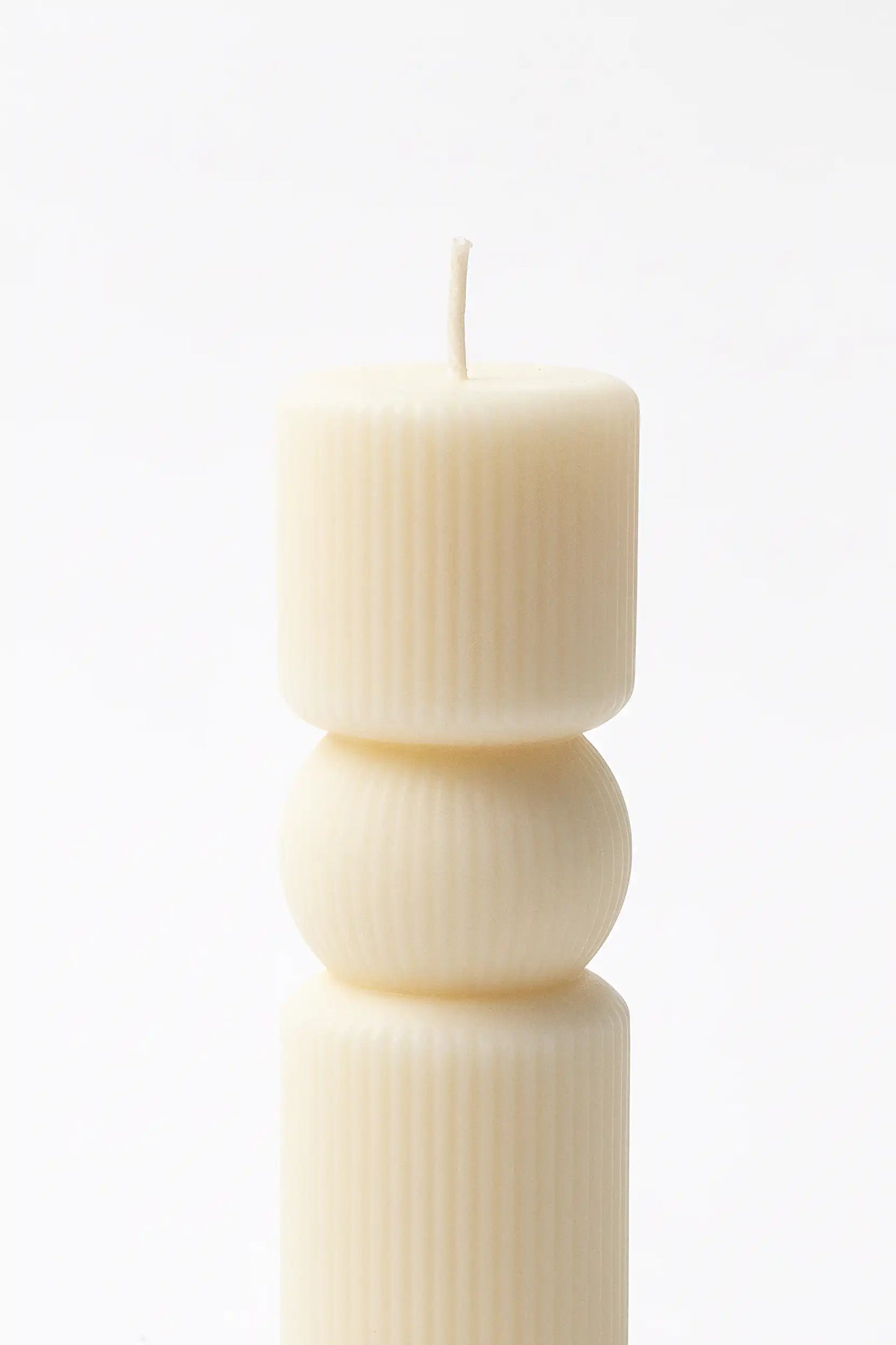white pillar candle with a textured design on a white background