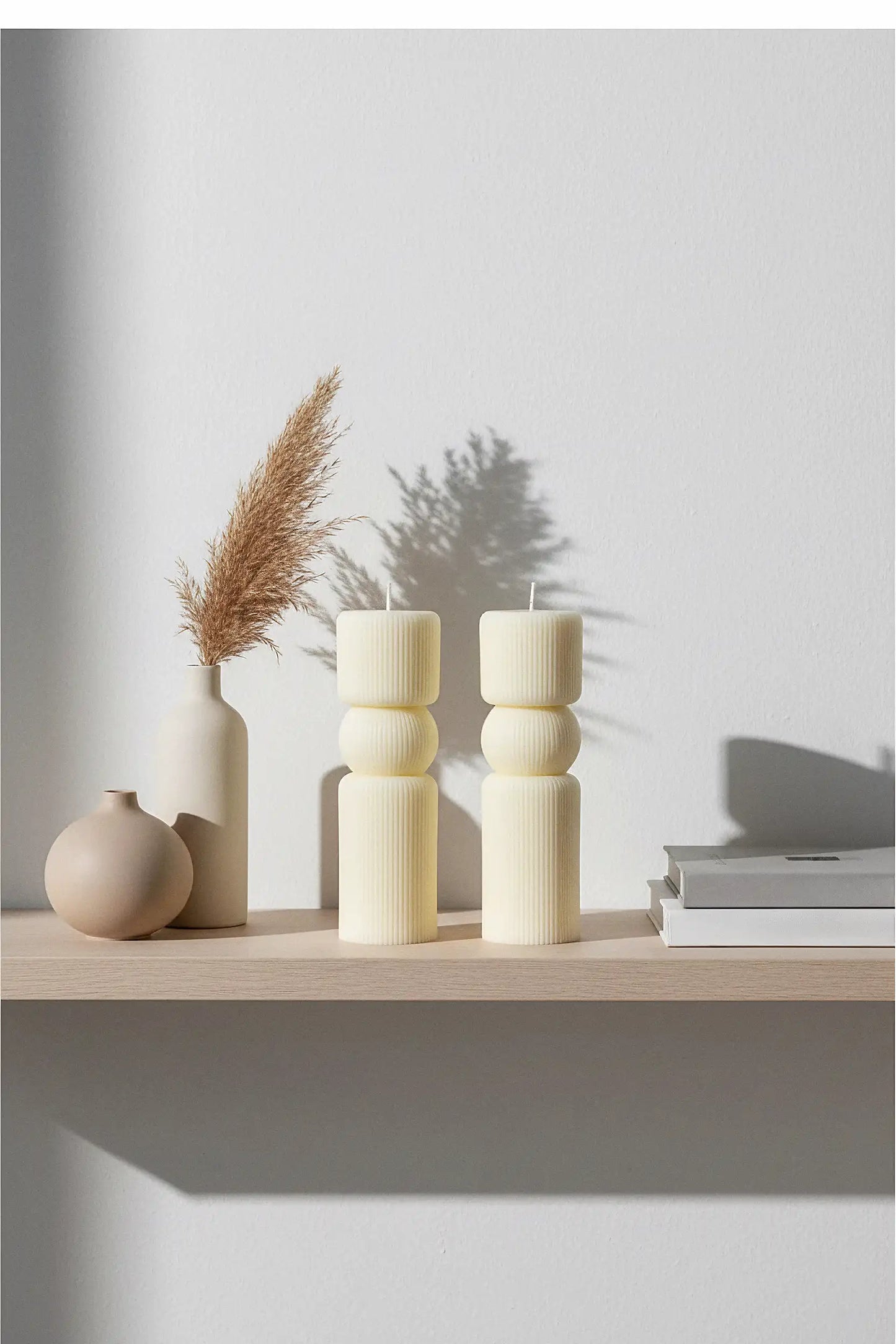 Decorative pillar candles and vases on a wooden surface with a light background